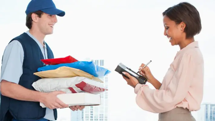 Businesswoman signing for package in office