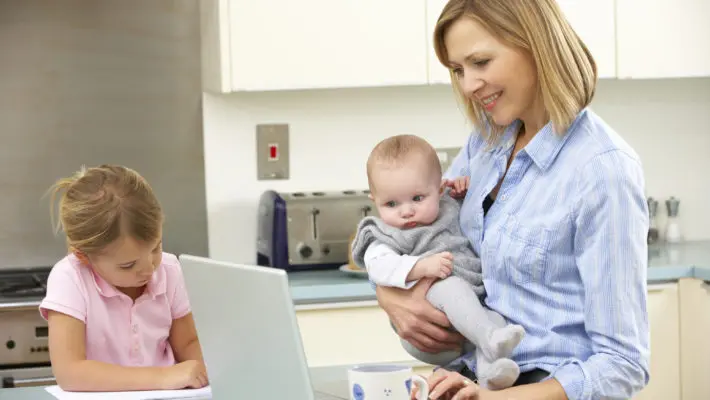 Mother with children using laptop in kitchen