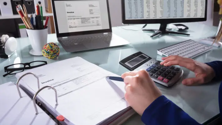 Close-up,Of,A,Businessperson’s,Hand,Calculating,Invoice,At,Workplace