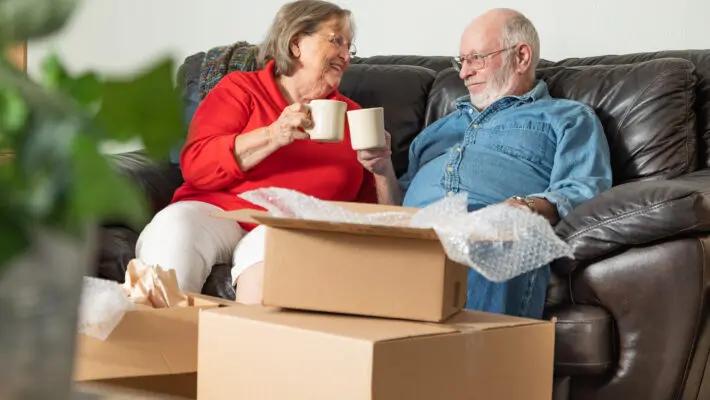 Tired,Senior,Adult,Couple,Resting,On,Couch,With,Cups,Of