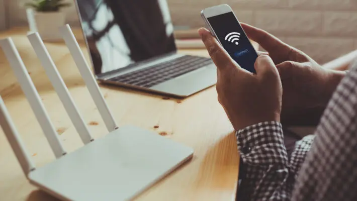 Closeup,Of,A,Wifi,Router,And,A,Man,Using,Smartphone
