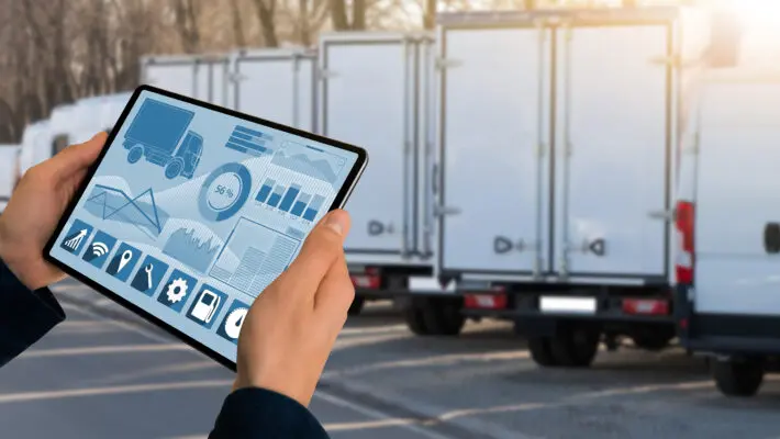 Manager,With,A,Digital,Tablet,On,The,Background,Of,Trucks.