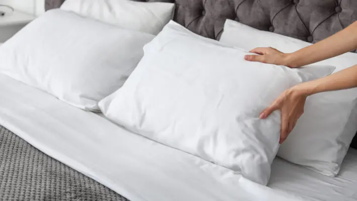 Young,Woman,Plumping,White,Pillow,On,Bed,,Closeup
