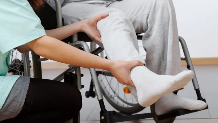 Young,Physiotherapist,Exercising,With,Elder,Disabled,Person