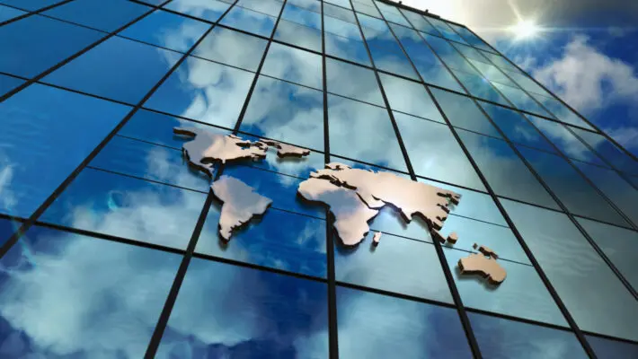 World,Map,Sign,On,Glass,Skyscraper.,Sky,And,Sun,Rays