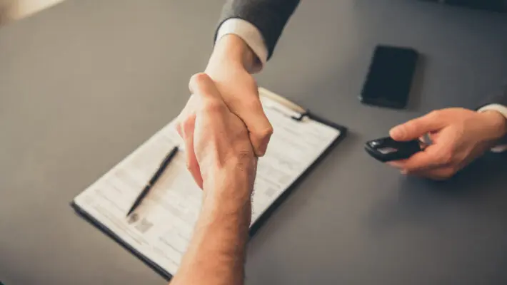 Visiting,Car,Dealership.,Men,Are,Shaking,Hands,While,Signing,Documents