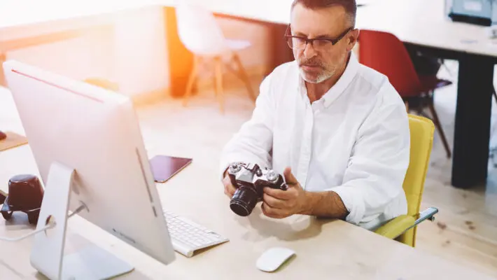 Male programmer 50 years old looking picture made by colleague a