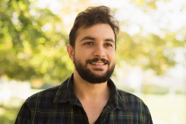 Bearded man in outdoors park. Smiling disheveled