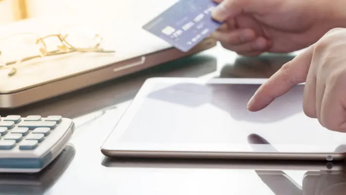 Man,Using,His,Digital,Tablet,While,Holding,A,Credit,Card