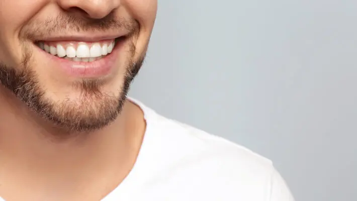 Young,Man,With,Beautiful,Smile,On,Grey,Background.,Teeth,Whitening