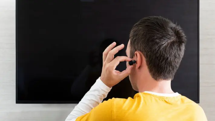 A,Man,Sticks,Headphones,In,His,Ear,Against,The,Background