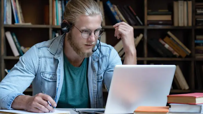 Focused,Young,Man,Student,Wear,Headset,Look,At,Laptop,Screen