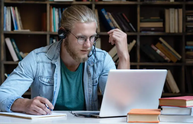 Focused,Young,Man,Student,Wear,Headset,Look,At,Laptop,Screen