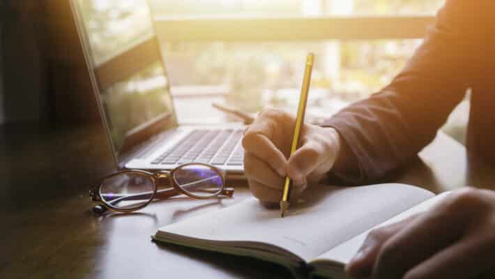 Young,Male,Student,Writes,Information,From,Portable,Net-book,While,Prepare